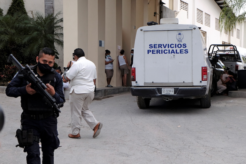 A police officer keeps watch as a vehicle from the coroner's office is parked at the entrance to a hotel after two suspected drug gang members were shot dead in a beachfront clash near Cancun Mexico November 4, 2021. u00e2u20acu201d Reuters/Paola Chiomante pic