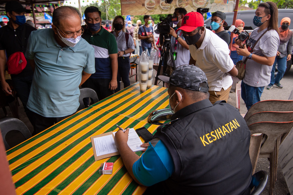 A Jasin health official issuing a compound to the organiser of a Barisan Nasional (BN) event at Medan Selera Selandar in Selandar, November 14, 2021. — Picture by Shafwan Zaidon