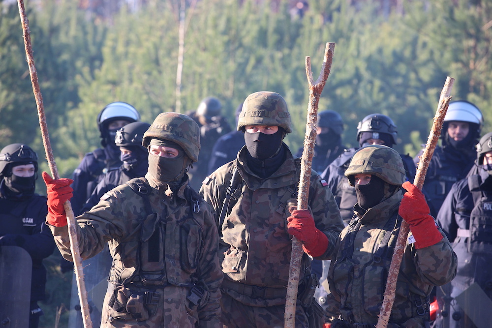 Polish service members and police officers are seen behind a barbed wire fence near the Belarusian-Polish border in an attempt to cross it in the Grodno region, Belarus November 9, 2021. u00e2u20acu201d Leonid Scheglov/BelTA/Handout via Reuters pic