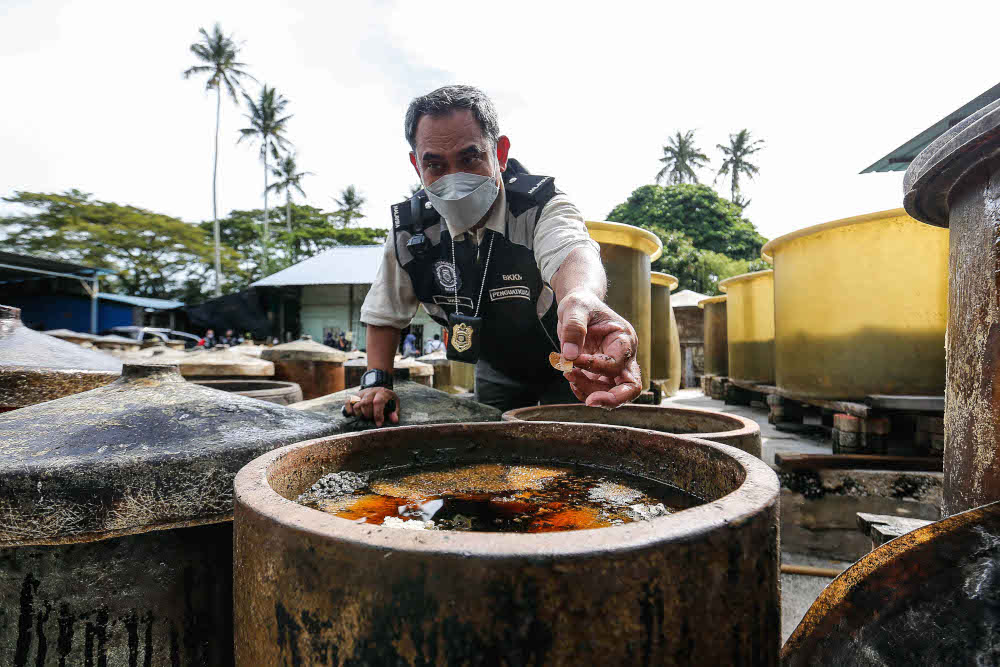 Head of Penang Food Safety and Quality Division for Ministry of Health Mohd Wazir Khalid checking a few of the soy sauce containers during an operation near Butterworth on November 11, 2021. — Picture by Sayuti Zainudin