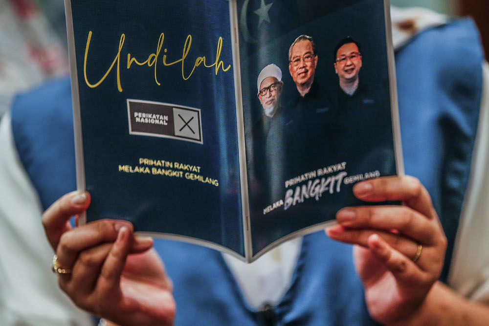 A Perikatan Nasional Srikandi member reads a Perikatan Nasional manifesto book during the launch at the Glenmarie Hotel and Resort November 14, 2021. u00e2u20acu2022 Picture by Hari Anggara