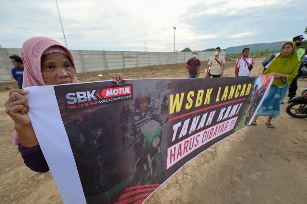 Local resident Suyatni (left), who claims to own land used for the development of the Mandalika International Circuit, holding a banner during a protest in front of the circuit in Kuta Mandalika November 17, 2021. — AFP pic