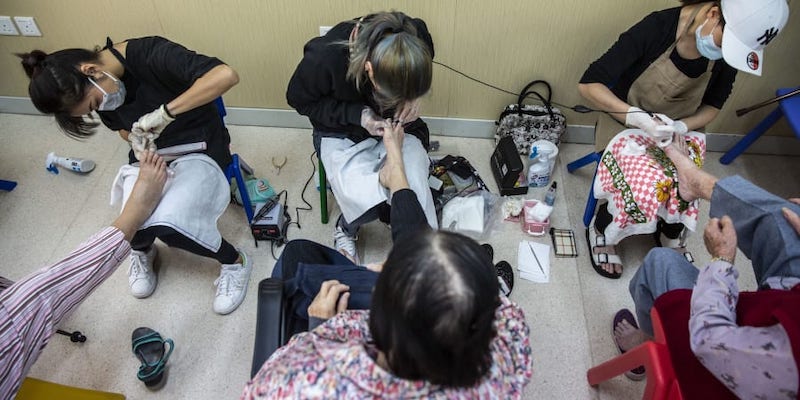 Volunteer manicurists (top) giving pedicures to low-income elderly people (bottom) at a community centre for the elderly in Hong Kong. u00e2u20acu201d AFP pic