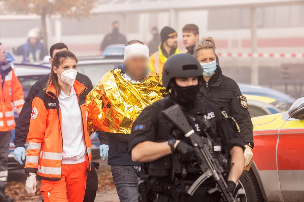 Policemen and rescue workers walk with a detained man on November 6, 2021 in Seubersdorf, southern Germany, after several people were wounded in a knife attack on a high-speed train. u00e2u20acu201dAFP picnn