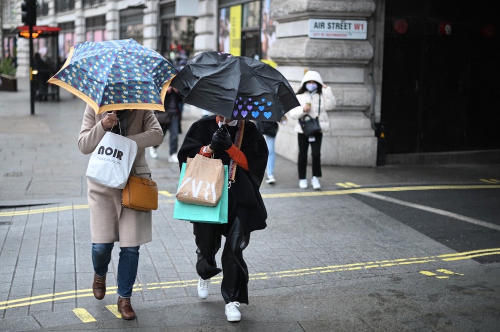 Shoppers shelter from the rain beneath umbrellas as they they carry their purchases in shopping bags on Black Friday in central London, on November 26, 2021. u00e2u20acu201d AFP picnn