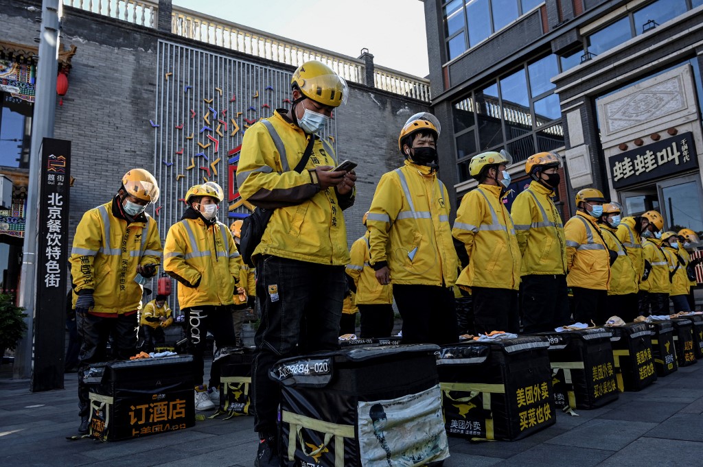 This photo taken on October 19, 2021 shows food delivery drivers for online shopping platform Meituan standing in formation before starting their work along a street in Beijing. u00e2u20acu201d AFP pic