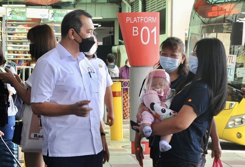 Mohd Solihan Badri (left) greets travellers from Singapore at the Larkin Sentral Bus Terminal in Johor Baru November 29, 2021. u00e2u20acu201d Picture by Ben Tan