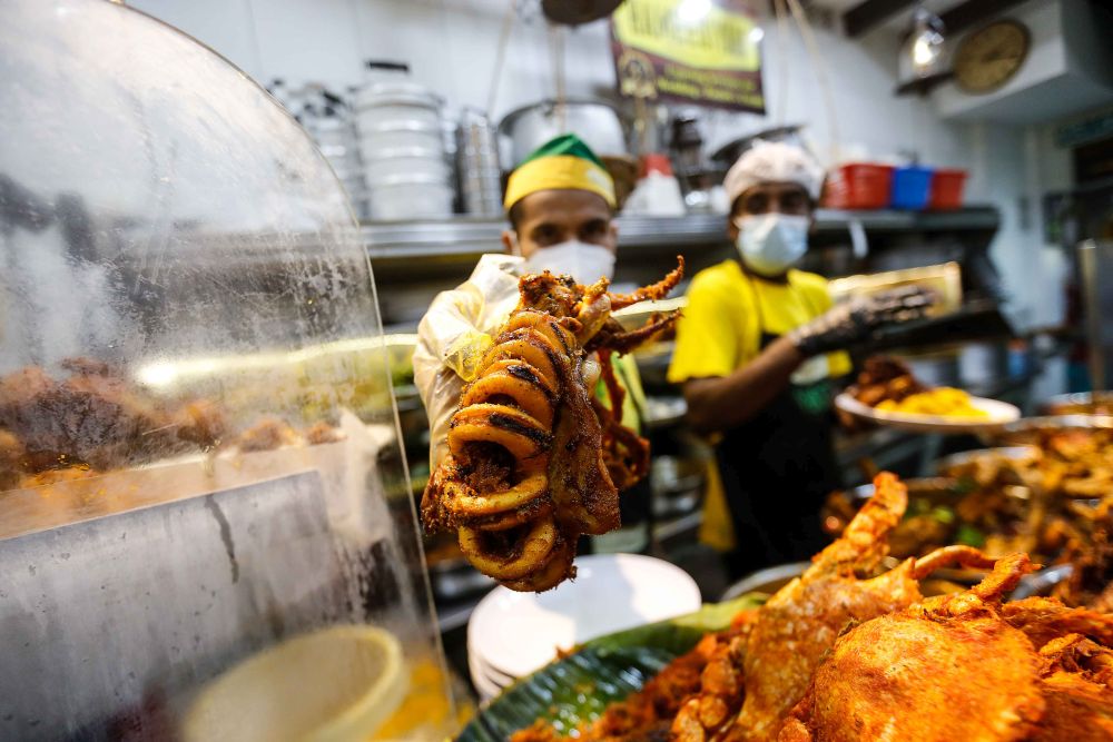 A Nasi Kandar Hameediyah staff holds up fried calamari rings at the restaurant on November 24, 2021. u00e2u20acu201d Picture by Sayuti Zainudin