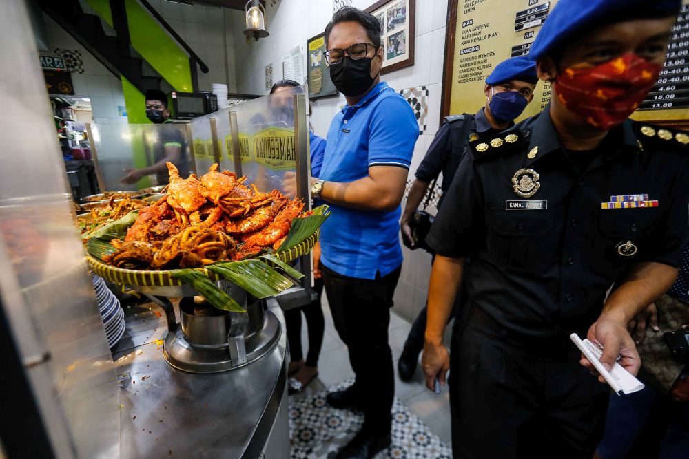 Ministry of Domestic Trade and Consumer Affairs personnel are pictured at Nasi Kandar Hameediyah after a complaint of overpriced calamari rings went viral November 24, 2021. — Picture by Sayuti Zainudin