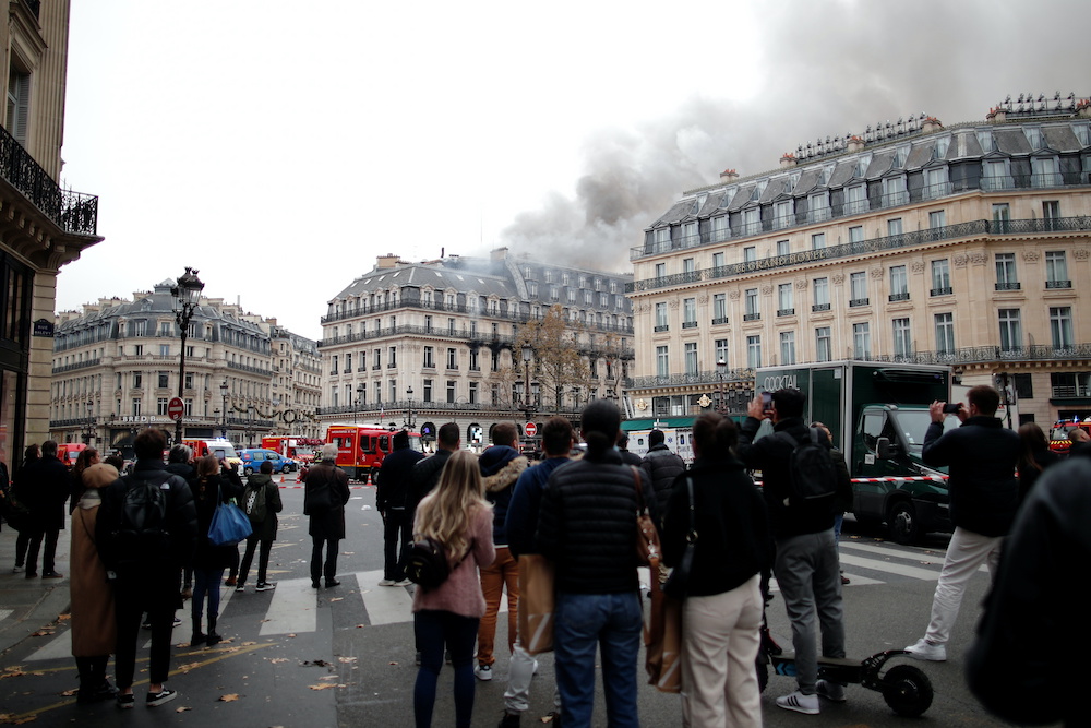 People watch as smoke billows from a building affected by a fire near the Opera Garnier in Paris, France, November 20, 2021. u00e2u20acu2022 Reutersnn
