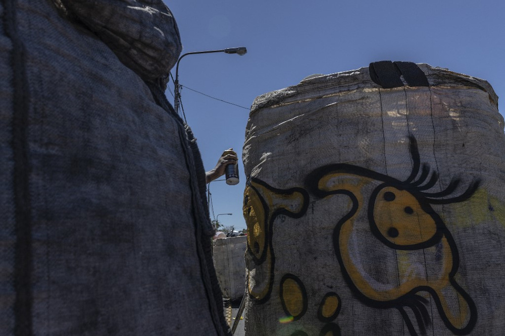 Naledi Chai, a graffiti artist, sprays a reclaimeru00e2u20acu2122s trolley as part of an initiative to make their graffiti art mobile and make reclaimers more visible and identifiable in Johannesburg on November 2, 2021. u00e2u20acu201d AFP pic
