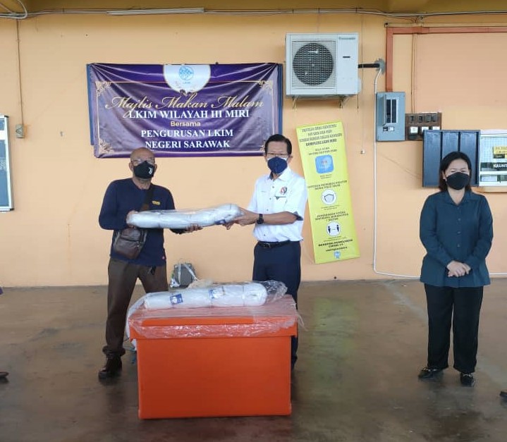 Lee (centre) presents fishing net, life jacket and a cold box to a fisherman, assistant Agriculture officer Awing Ngerong looks on. u00e2u20acu2022 Borneo Post pic