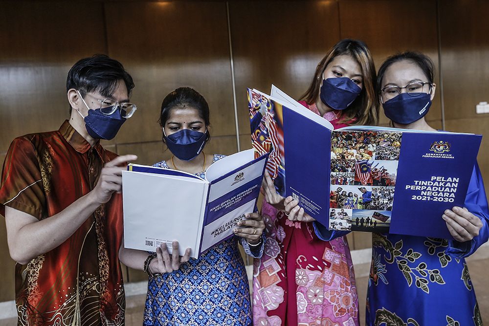 Members of the public are seen reading a copy of the National Unity Action Plan and the Kami @Keluarga Malaysia Unity Plan at the Kuala Lumpur Convention Centre November 28, 2021. — Picture by Hari Anggara