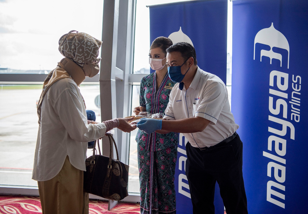 Malaysia Airlines group chief operations officer Ahmad Luqman distributes cookies to departing passengers on the first VTL flight MH603 from KLIA to Singapore, November 29, 2021. u00e2u20acu201d Picture courtesy of Malaysia Airlinesnn