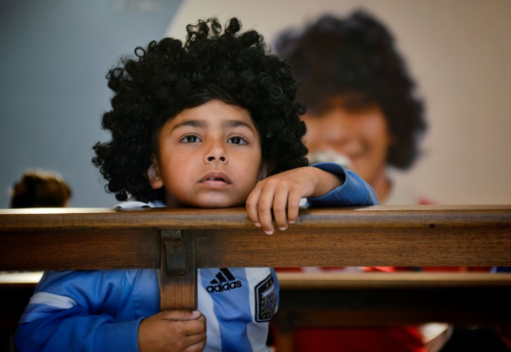 A boy wearing a wig resembling Diego Maradona looks on in a sanctuary to honour Maradona in La Paternal, on the first anniversary of his death, Buenos Aires November 25, 2021. u00e2u20acu201d Reuters picnn
