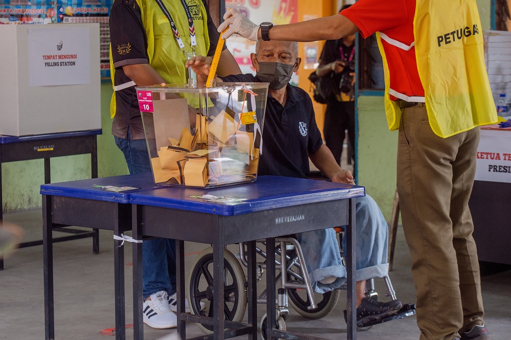 An elderly man casts his vote in Durian Tunggal during the Melaka state election on November 20, 2021. 