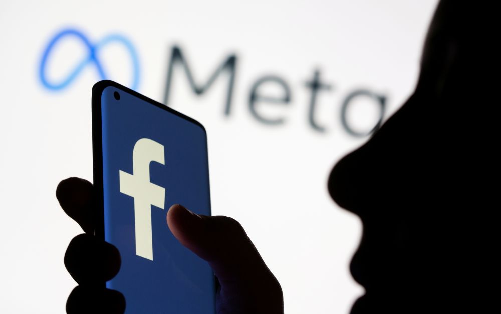 A woman holds smartphone with Facebook logo in front of a logo of Meta in this illustration picture taken October 28, 2021. u00e2u20acu201d Reuters pic
