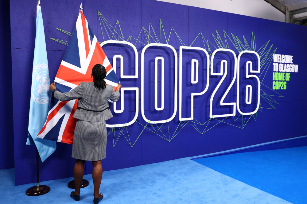 An employee adjusts flags before the arrival of leaders for the UN Climate Change Conference (COP26) in Glasgow, Scotland November 1, 2021. u00e2u20acu201d Adrian Dennis/Pool pic via Reuters