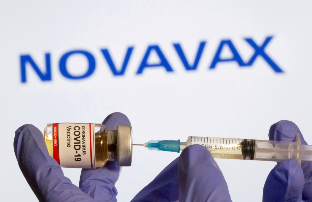 A woman holds a small bottle labelled with a u00e2u20acu02dcCoronavirus Covid-19 Vaccineu00e2u20acu2122 sticker and a medical syringe in front of displayed Novavax logo in this illustration taken on October 30, 2020. u00e2u20acu201d Reuters pic