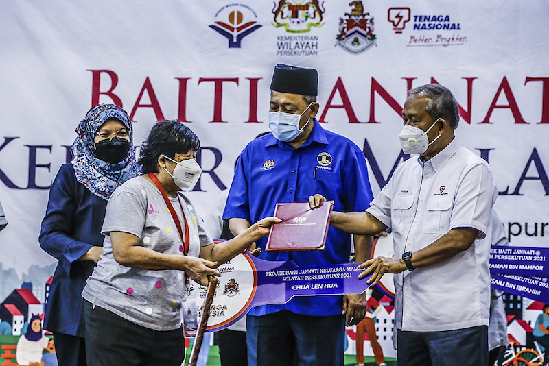 Tenaga Nasional Berhad Chairman, Datuk Seri Hasan Arifin (right) and Federal Territories Minister Datuk Seri Shahidan Kassim (centre) deliver a replica of the key to a recipient. — Picture by Hari Anggara
