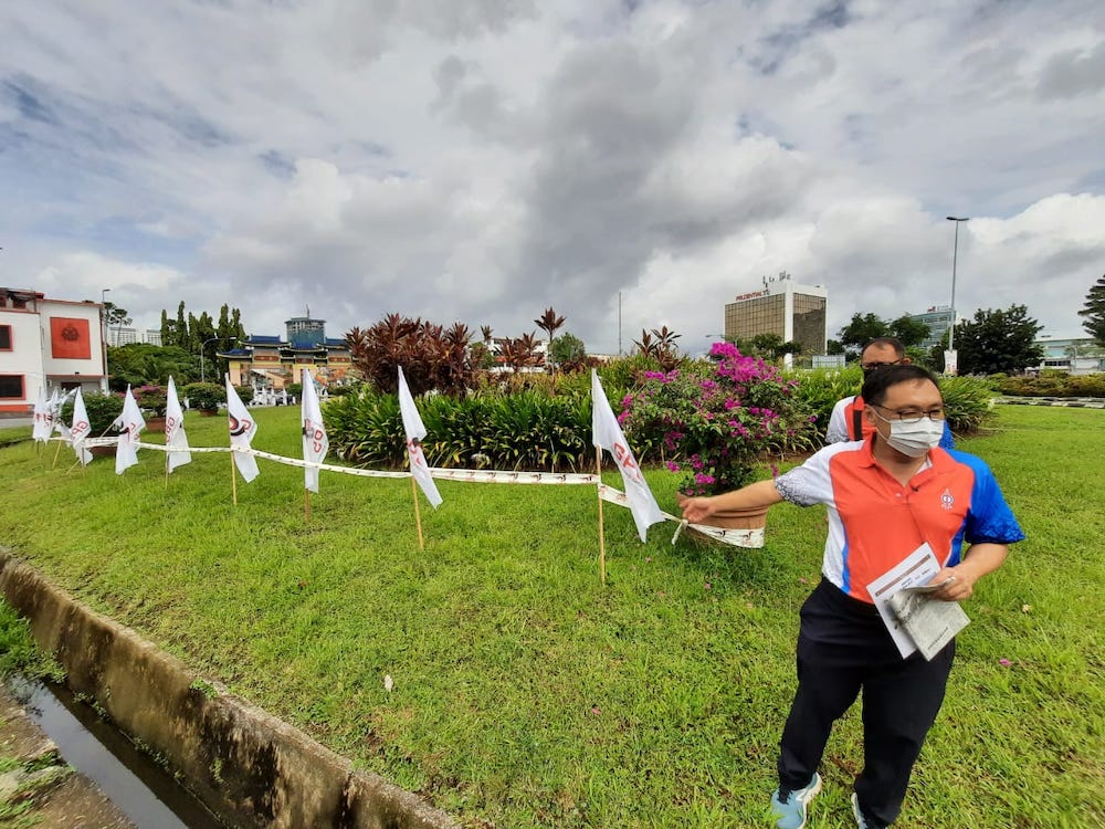 Chong pointing at the GPS flags put up at Padungan roundabout in front of the Kuchingu00e2u20acu2122s iconic u00e2u20acu02dcWhite Catu00e2u20acu2122 statue. u00e2u20acu201d Borneo Post pic