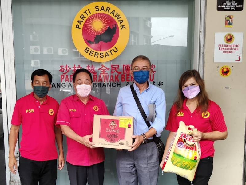 Wong (second left) hands over food aid to a recipient. u00e2u20acu201d Picture by Peter Boon