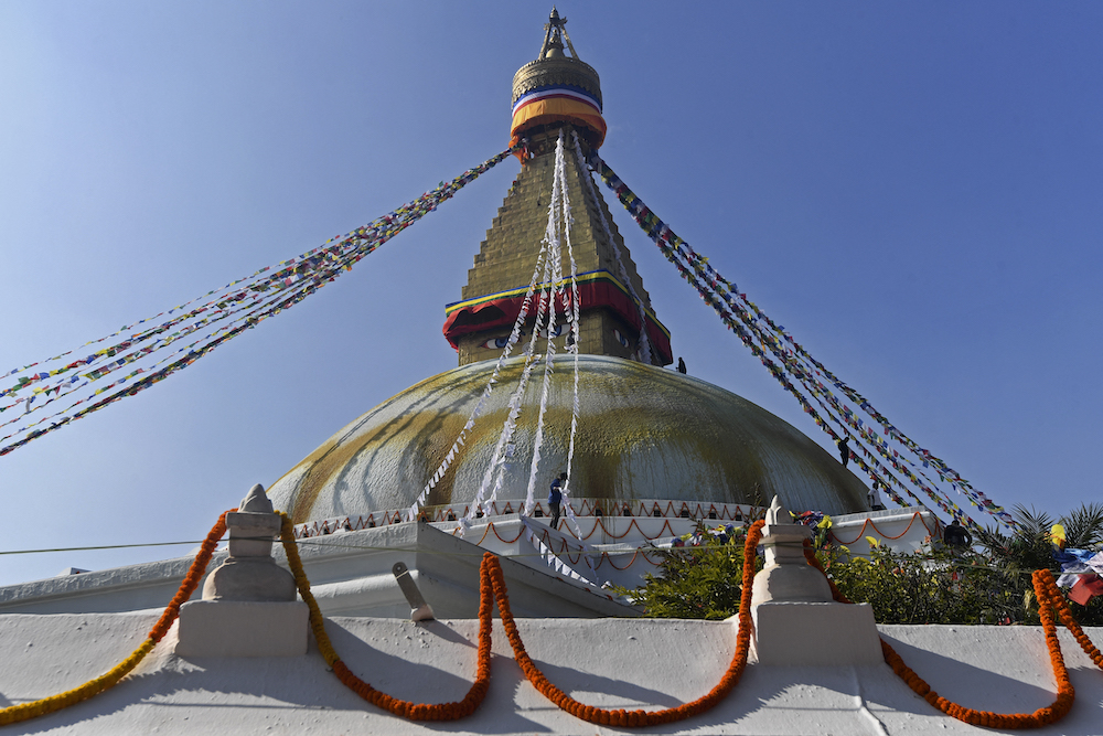 A Buddhist devotee hangs biodegradable prayer flags on Boudhanath stupa on the outskirts of Kathmandu December 18, 2021. u00e2u20acu201d AFP pic
