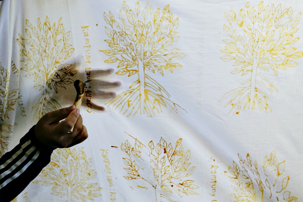 A mangrove batik worker draws a batik pattern on a white cotton cloth in Klaces village, Cilacap, Central Java province, Indonesia November 4, 2021. — Reuters pic