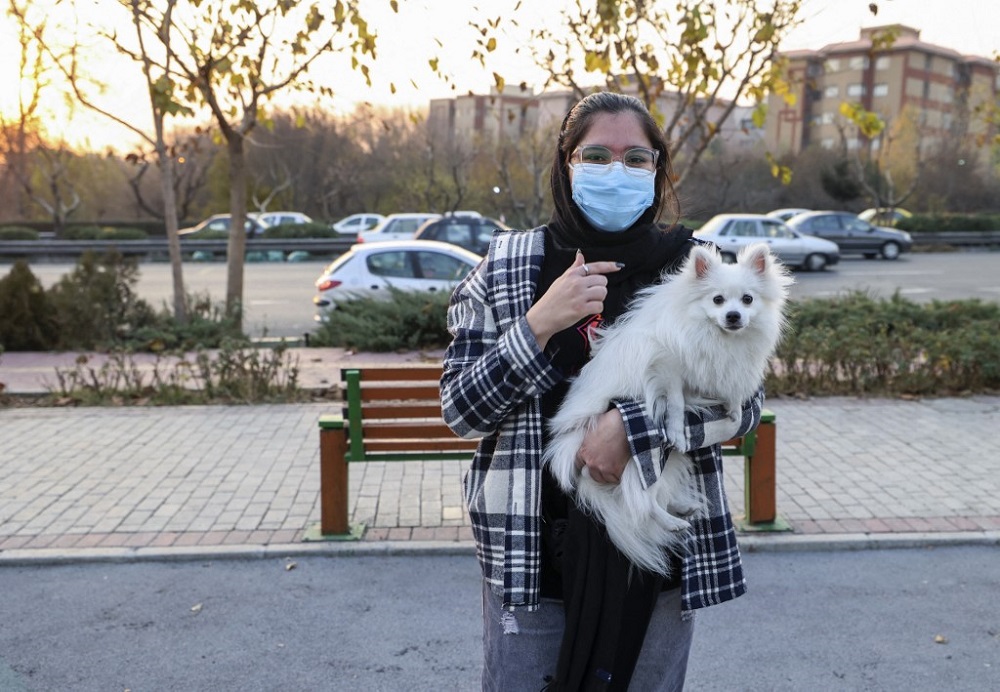 An Iranian woman poses for a picture with her dog at a park in the capital Tehran December 7, 2021. — AFP pic