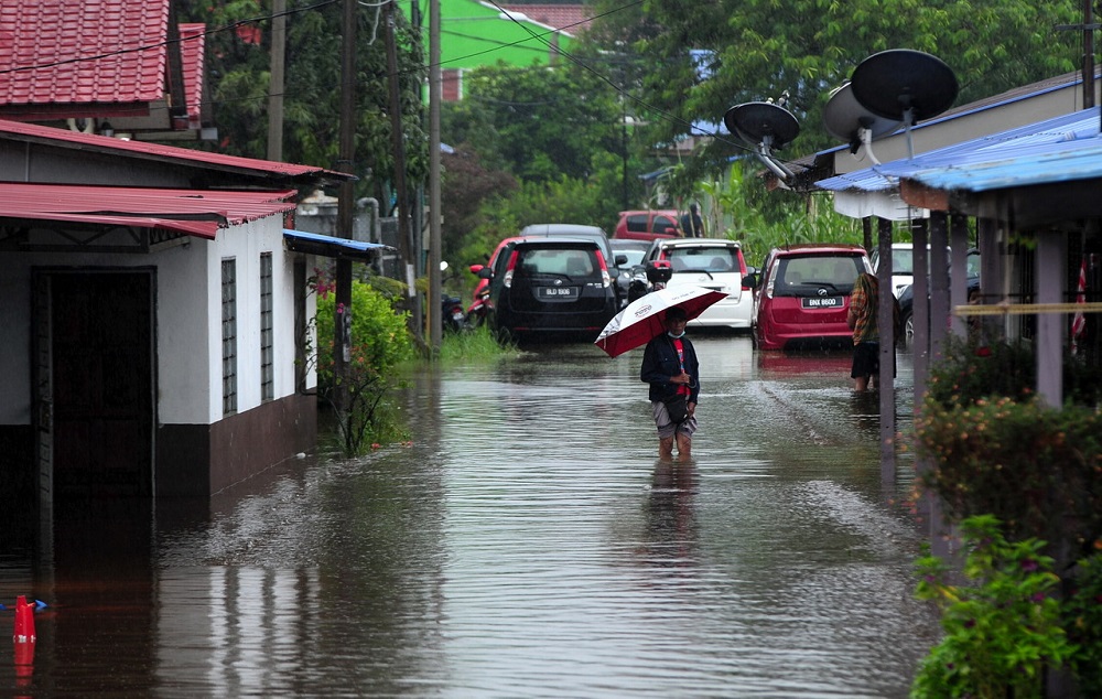 A man wades through flood water outside his house in Kampung Johan Setia in Klang December 18, 2021. — Bernama pic