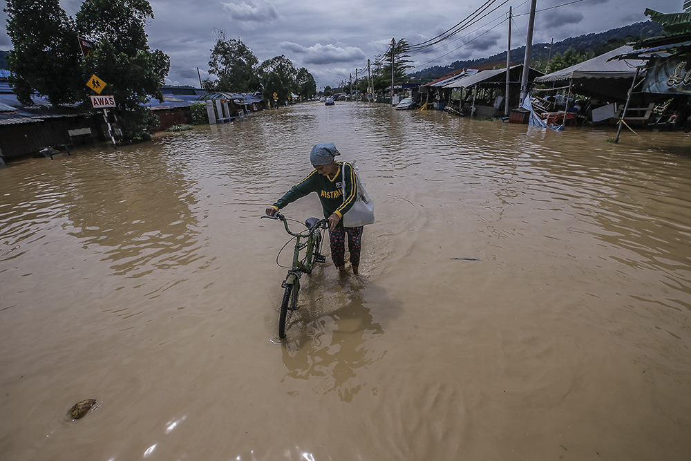 A flood victim pushes a bicycle through the floods in Hulu Langat December 19, 2021. u00e2u20acu201d Picture by Hari Anggara