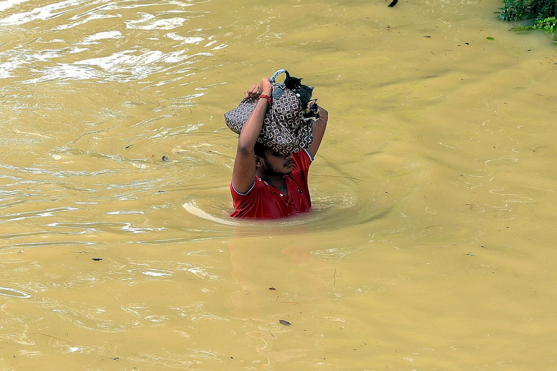 A resident wades through flood waters with his pets after being stranded in a flash flood in Sri Muda, Shah Alam 19 December 2021. u00e2u20acu201d Bernama pic