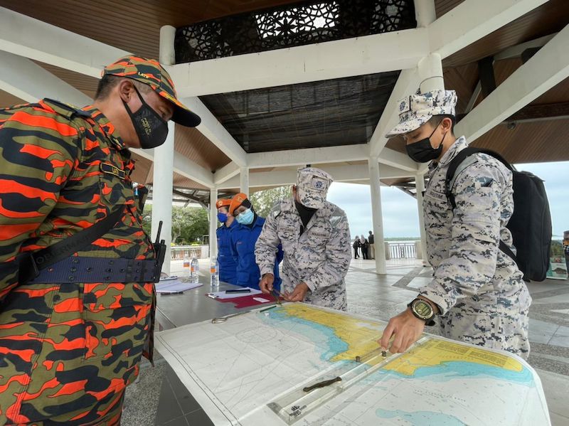 MMEA personnel together with the firefighters discussing the SAR operations off Telaga Air to find the missing boats. — Borneo Post pic