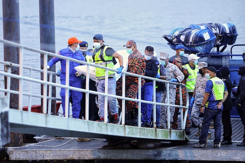 The body of the boat’s first-mate being brought to land following the SAR over the waters off Telaga Air. — Borneo Post pic