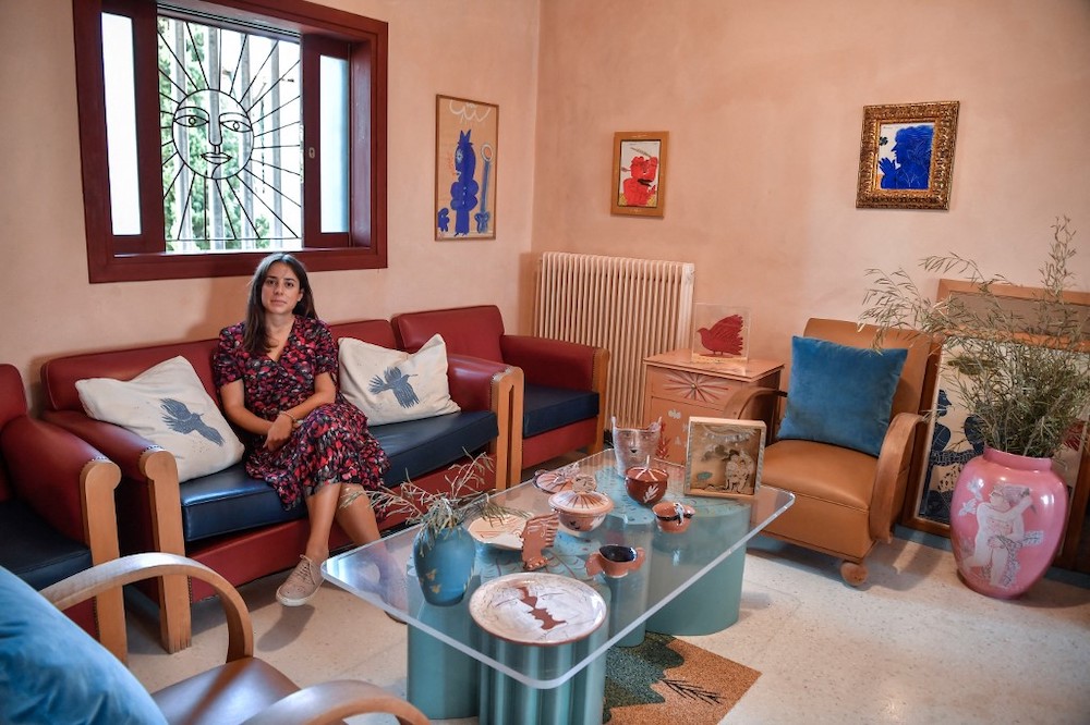 Viktoria Fassianou, daughter of Greek contemporary artist Alekos Fassianos, poses on a sofa surrounded by artworks and furnitures created by her father in his house in Athens, on September 29, 2021, prior to the opening in the fall of 2022 of a museum in