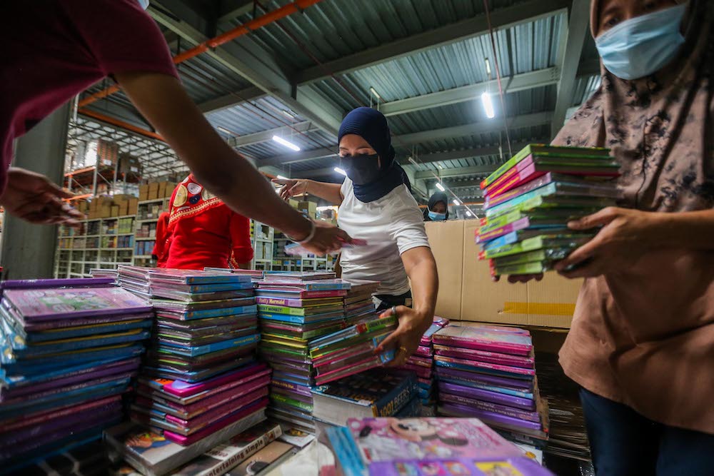 Workers sorting out damaged books and cleaning up the affected area due to floods last week at the BookXcess warehouse, Section 33 in Shah Alam December 28, 2021. u00e2u20acu201d Picture by Hari Anggara