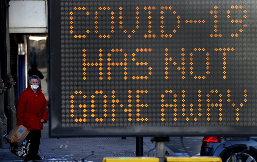 A woman wearing a face mask stands next to an information board offering advice about the coronavirus disease pandemic in Bolton, Britain, December 18, 2021. u00e2u20acu201d Reuters picnnnn