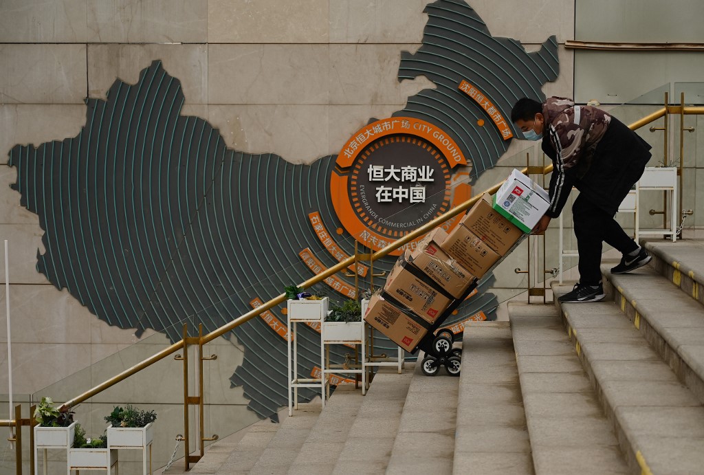 A worker pusher a cart in front of a sign showing Evergrande Groupu00e2u20acu2122s China operation at a housing complex by the property developer in Beijing on December 8, 2021. u00e2u20acu201d AFP pic