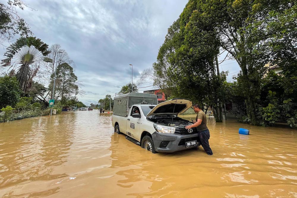 A man checks his car after it was caught in floodwater in Hulu Langat, December 19, 2021. — Picture by Hari Anggara