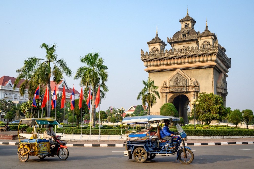 This file photo taken on March 12, 2020 shows traditional tuk tuks passing in front of the Patuxai war monument in the centre of Vientiane. Laos has announced plans on December 17, 2021 to partially re-open to foreign travellers in the new year. u00e2u20acu201d AFP p