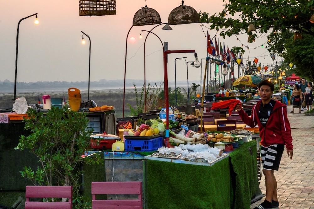This file photograph taken on March 12, 2020 shows an employee inviting customers at an open air restaurant on the banks of the Mekong river in Vientiane. Laos has announced plans on December 17, 2021. — AFP pic