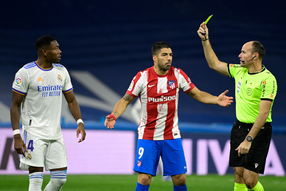 Referee Antonio Miguel Mateu Lahoz shows a yellow card to Real Madrid defender David Alaba and Atletico Madrid forward Luis Suarez during the Spanish league match at the Santiago Bernabeu stadium in Madrid, December 12, 2021. u00e2u20acu201d AFP pic 
