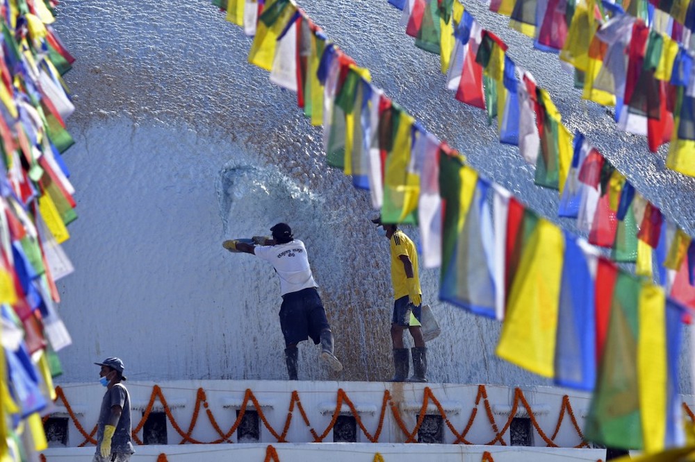 A Buddhist devotee splashes coloured water on Boudhanath stupa on the outskirts of Kathmandu on December 18, 2021. u00e2u20acu201d Reuters picnnn