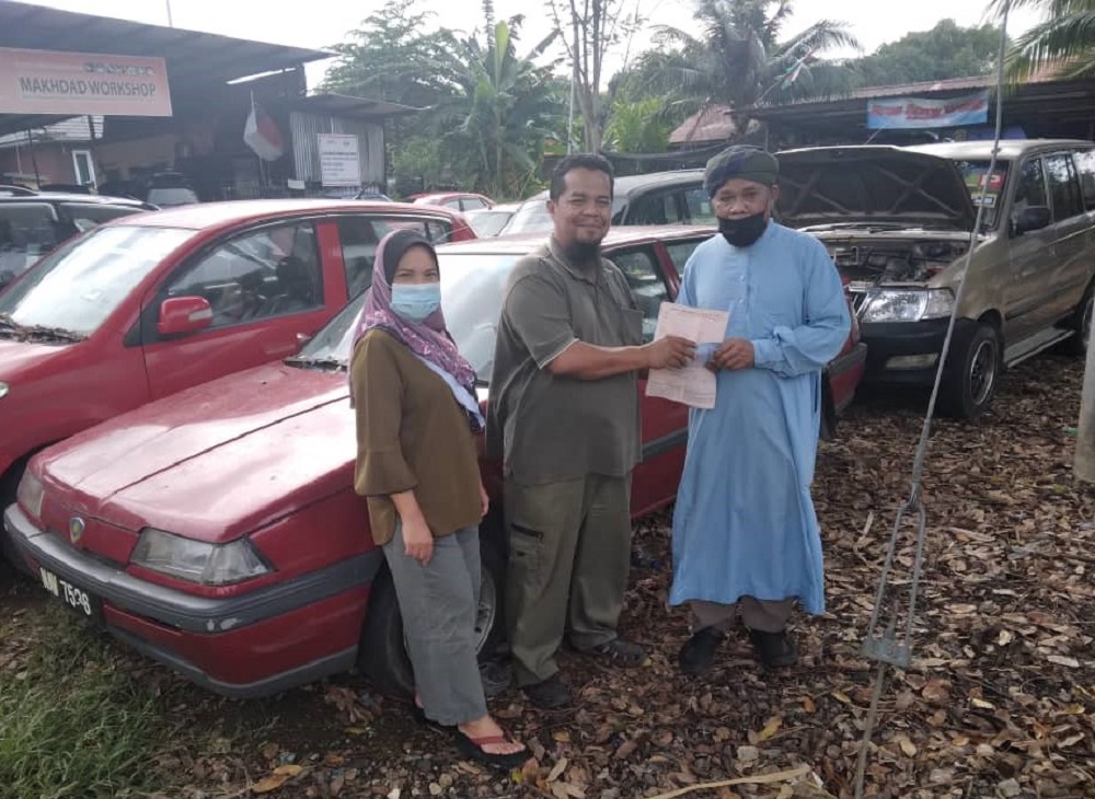 Shikh Muhammad (centre) felt elated after selling the second-hand Proton Iswara to Isa Abdul Ghani (right). u00e2u20acu2022 Picture via Shikh Muhammad Makhdad Haron