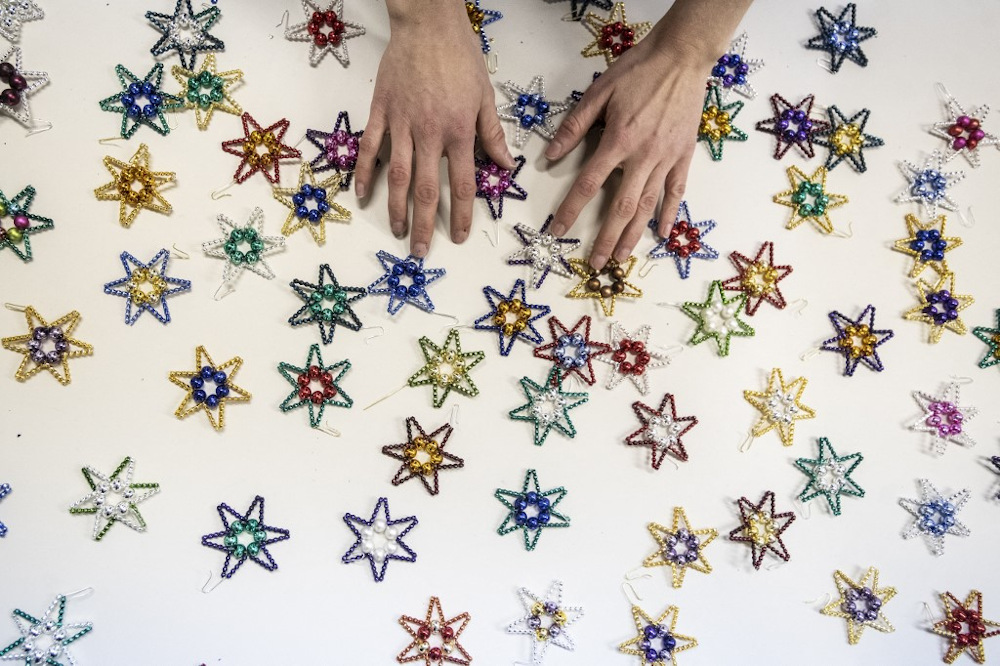A worker handles little stars as Christmas tree decorations made of from blown glass beads on December 14, 2021 in a small family factory in Ponikla village, North Bohemia in the Czech Republic. — AFP pic