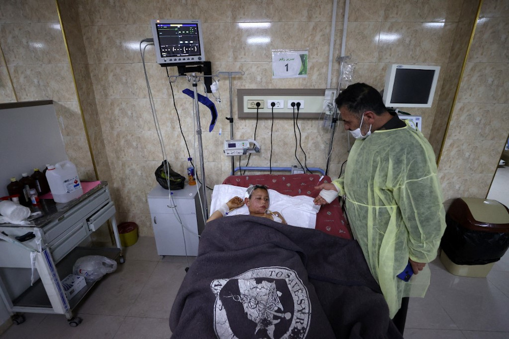 Ahmad Qassum, a Syrian who was injured along with his family in a US drone strike, stands by his son Mahmud as the latter lies on a bed at an ICU at a hospital of the Syrian American Medical Society (SAMS) in Idlib December 7, 2021. u00e2u20acu201d AFP pic