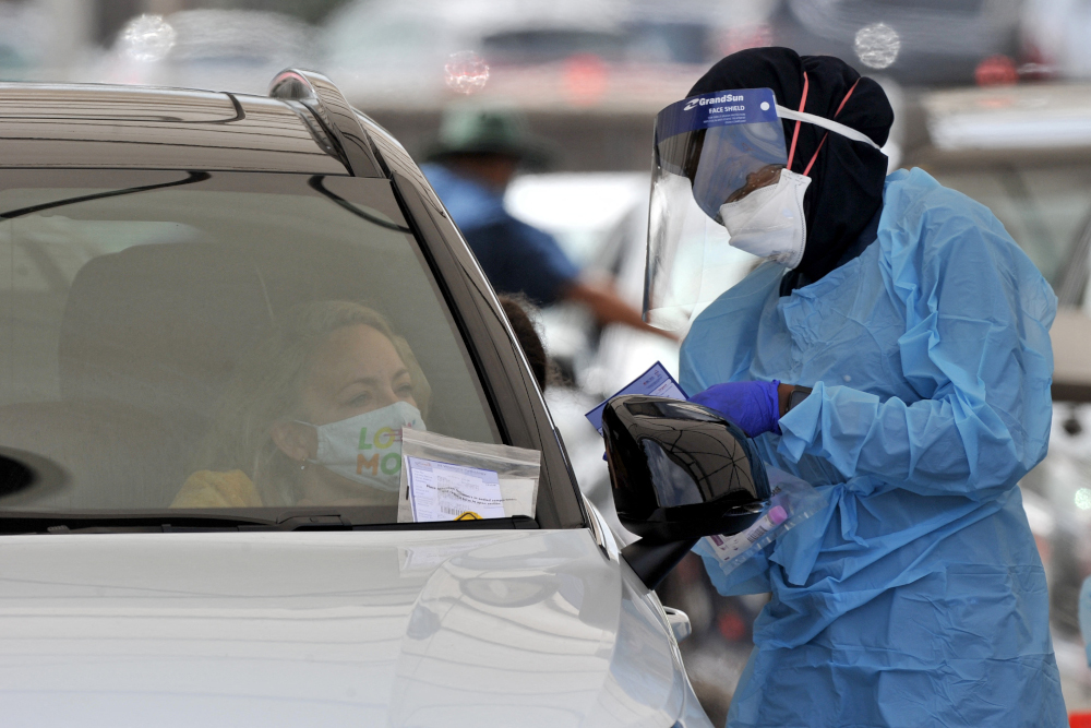 A health worker conducts a PCR test at the St Vincentu00e2u20acu2122s Bondi Beach Covid-19 drive through testing clinic December 22, 2021 in Sydney. u00e2u20acu201d AFP pic 