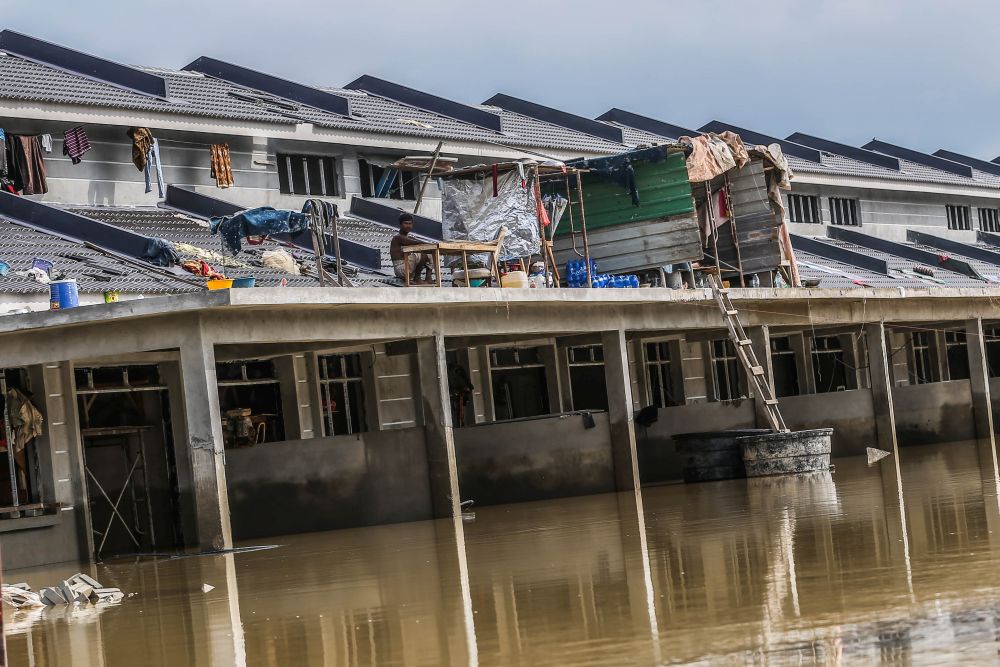 A man seeks shelter from floodwaters on the top of his roof in Kampung Labohan Dagang, Banting December 22, 2021. u00e2u20acu201d Picture by Hari Anggara