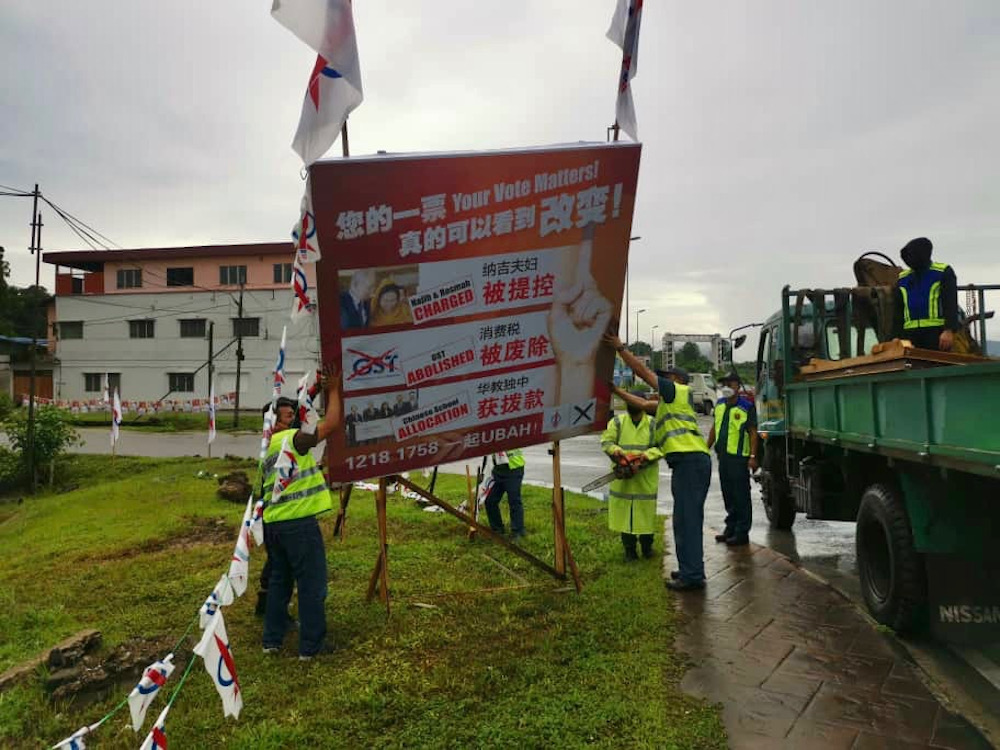 Members of the ECu00e2u20acu2122s monitoring task force use a chainsaw to take down DAP candidate Kelvin Yiiu00e2u20acu2122s billboard in Highfields, Batu Kawah. u00e2u20acu201d Picture courtesy of Sarawak DAP 