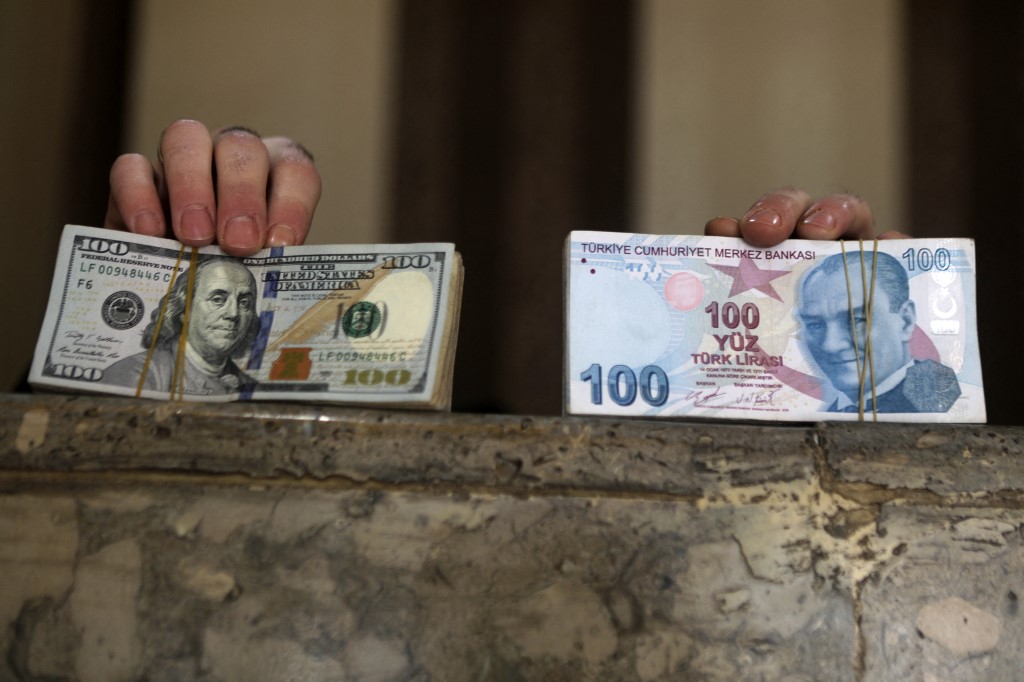 A Syrian man holds stacks of US dollars (left) and Turkish currency in the rebel-held city of al-Bab in Syriau00e2u20acu2122s northern Aleppo province on the border with Turkey, on December 5, 2021. u00e2u20acu201d AFP pic
